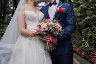 Gelin ve damat parkta düğün buketi tutuyorlar.