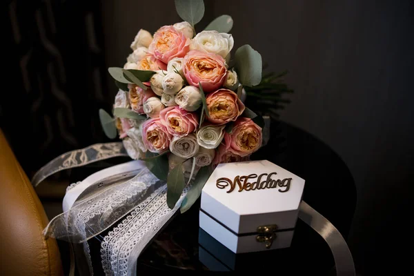 wedding rings with a box near a bouquet