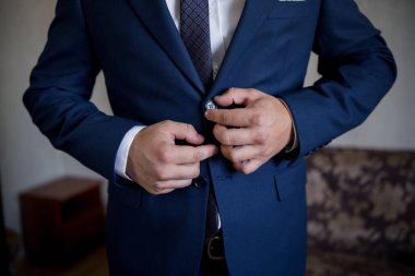 Adam ceketin düğmesini takım elbiseyle bağlar.