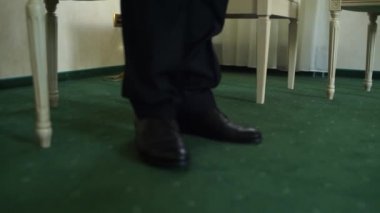 Ayakkabılı bir adam odada dolaşıyor.
