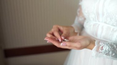 Gelin elinde küpeler tutuyor.