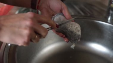 Kadın somon kabuğunu soyar.