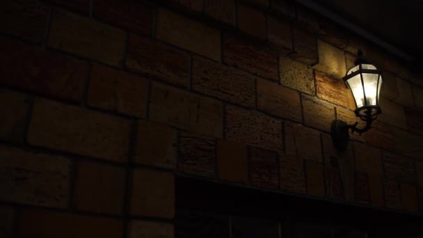Laterne Leuchtet Nachts Auf Einer Ziegelmauer — Stockvideo