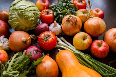 Soğan, sarımsak, domates, yeşiller, maydanoz, roka, lahana, elma, pancar, havuç, balkabağı, ahşap bir masaya uzan.