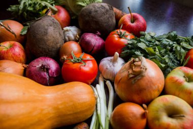 Soğan, sarımsak, domates, yeşiller, maydanoz, roka, lahana, elma, pancar, havuç, balkabağı, ahşap bir masaya uzan.