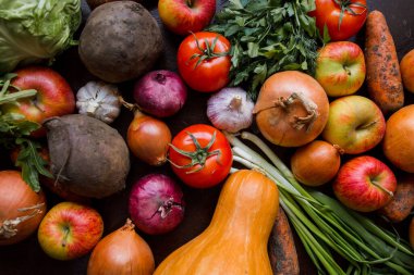 Soğan, sarımsak, domates, yeşiller, maydanoz, roka, lahana, elma, pancar, havuç, balkabağı, ahşap bir masaya uzan.