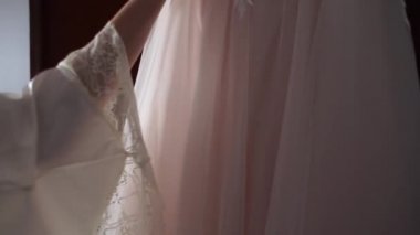 Gelin elinde bir gelinlik tutuyor.