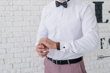 Adam odada takım elbise giyer.