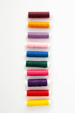 Beyaz arkaplandaki çok renkli ipliklerin makaraları