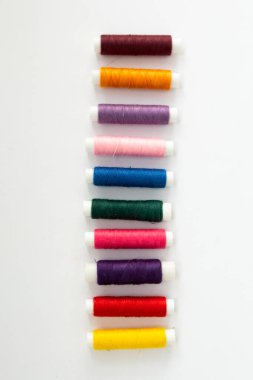 Beyaz arkaplandaki çok renkli ipliklerin makaraları