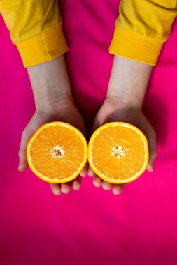 Pembe arka planda çocuk ellerinde turuncu