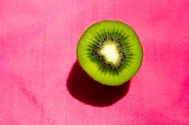 Pembe parlak arka planda dilimlenmiş kivi.