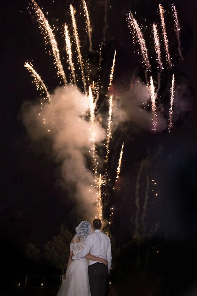 the bride and groom look at the fireworks