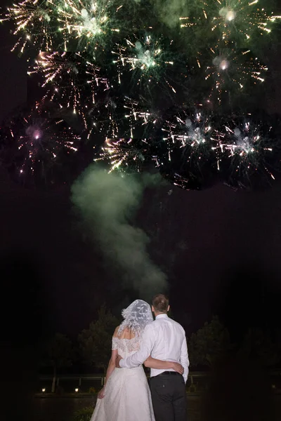 the bride and groom look at the fireworks