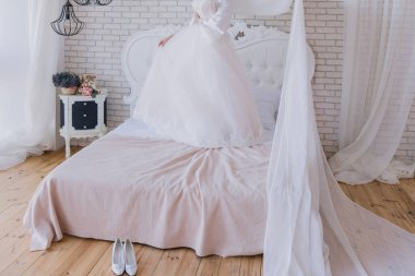 Peignoir giymiş gelin gelinliğini tutuyor.