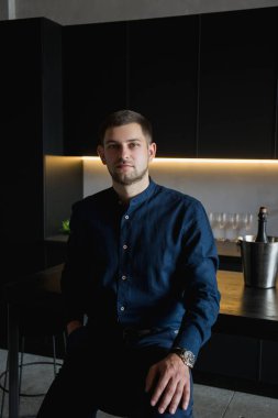 Siyah mutfakta mavi gömlekli adam.