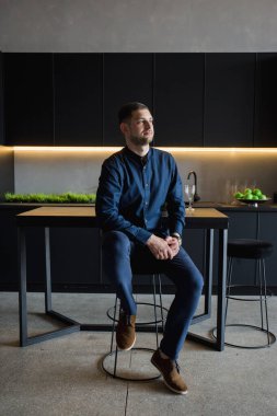 Siyah mutfakta mavi gömlekli adam.