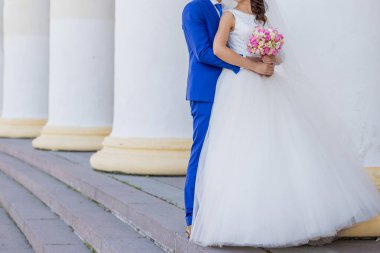 Gelin ve damat sütunlarla birlikte binanın yanında.