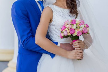 Gelin ve damat sütunlarla birlikte binanın yanında.