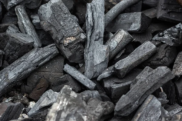 Black charcoal texture background. Natural wood charcoal, traditional charcoal or hard wood charcoal. Pile of charcoal. Details on the surface of charcoal. — Stock Photo, Image