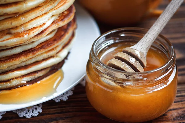 Pilha de deliciosas panquecas caseiras com mel em placa branca sobre fundo de madeira. Pequeno-almoço saudável, de perto. Dia das Panquecas. Alta pilha de panquecas rasas DOF . — Fotografia de Stock