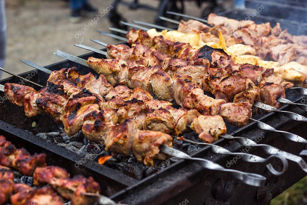 Marinated shashlik preparing on a barbecue grill over charcoal. Shashlik or Shish popular in Eastern Europe. (skewered meat) was originally made of lamb. Roast Kebabs On BBQ Grill. Stock