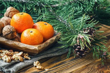 Yılbaşı yeni yıl kompozisyon kış tatil kutlama kavramı sembol mandalina mandalina clementine fındık çam kozalakları köknar dalları rustik tarzı eski ahşap tahta seçici odak Festival tebrik kartı