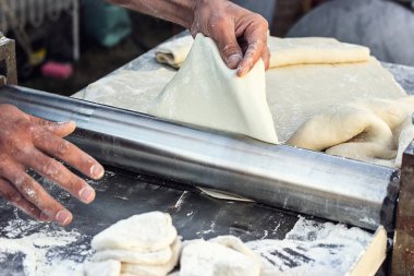 Şef yapımı hamur hamur açma ekmek makinesi şekillendirme hamur şekillendirme Baker pasta metal işleri tablo closeup eller işlem ekmek Hıngel hamur rulo makine ince makarna yaprak üstten görünüm hazırlama haddelenmiş.