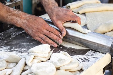 Şef yapımı hamur hamur açma ekmek makinesi şekillendirme hamur şekillendirme Baker pasta metal işleri tablo closeup eller işlem ekmek Hıngel hamur rulo makine ince makarna yaprak üstten görünüm hazırlama haddelenmiş.