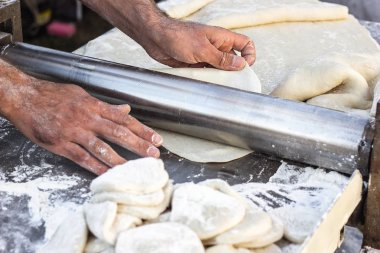 Şef yapımı hamur hamur açma ekmek makinesi şekillendirme hamur şekillendirme Baker pasta metal işleri tablo closeup eller işlem ekmek Hıngel hamur rulo makine ince makarna yaprak üstten görünüm hazırlama haddelenmiş.