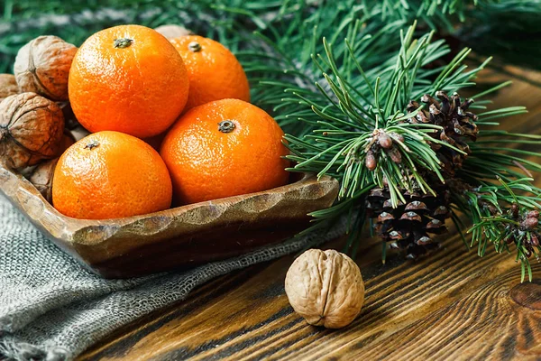 Christmas New Year composition winter holiday celebration concept symbol tangerines mandarin clementine nuts pine cones fir branches rustic style old wooden board selective focus festive greeting card — Stock Photo, Image