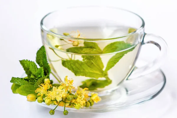 Taza de té de hierbas con flores de tilo, miel y menta en taza transparente aislado en blanco —  Fotos de Stock