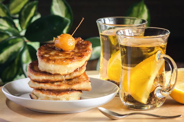 Stack of delicious pancakes on white plate with berries in syrup and honey and tea with lemon for healthy breakfast - homemade healthy vegetarian food — Stock Photo, Image