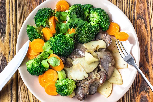 Hígado de pollo frito con verduras manzanas brócoli zanahorias cebollas y hierbas en un plato en la mesa de madera, vista horizontal desde arriba. Vista superior de la comida sabrosa . — Foto de Stock