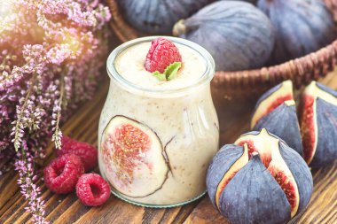 Güzel sağlıklı meze incir meyve güler yüzlü milkshake cam dekore edilmiş taze incir pembe ahududu üstten görünüm. Doğal detoks sıvı dondurma. Yoğurt kokteyl tatlı ahşap arka plan.