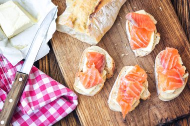 Parmak gıda. Meze kanepeler sandviçler baget, somon ve ahşap arka plan üzerinde rustik ahşap tahta üzerine tereyağı ile. Üst görüntülemek, kopya alanı, yatay