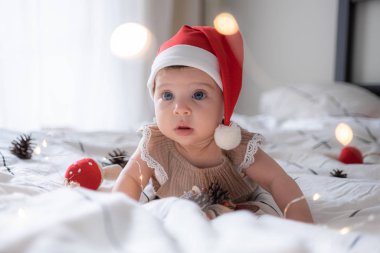 Kırmızı Noel Baba şapkalı, ışıklı küçük tatlı kız portresi.