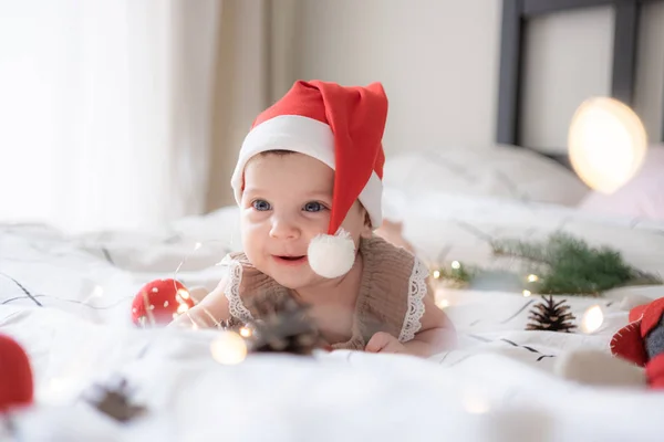 Kırmızı Noel Baba şapkalı, ışıklı küçük tatlı kız portresi.