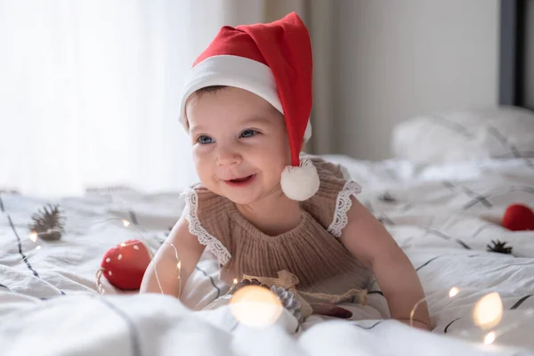 Kırmızı Noel Baba şapkalı, ışıklı küçük tatlı kız portresi.
