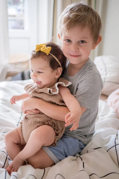 Little infant baby girl sitting together with her toddler brother — Stock Photo, Image