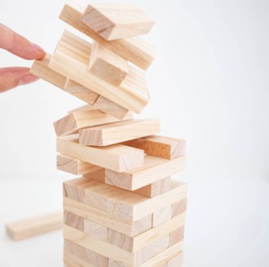 Düşen ahşap tuğla kulesine ve bir ele yakın durun. Finans sonbahar konsepti. Planlama, risk ve iş stratejisi, iş adamı ve mühendis bir kuleye tahta blok yerleştirmek.