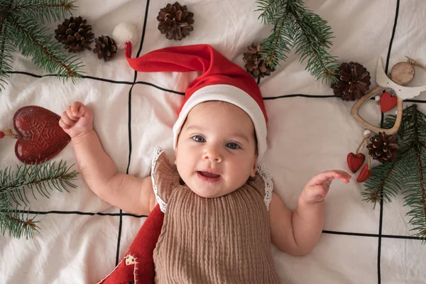 Kırmızı Noel Baba şapkalı, ışık manzaralı küçük şirin kız portresi. Noel tatili 