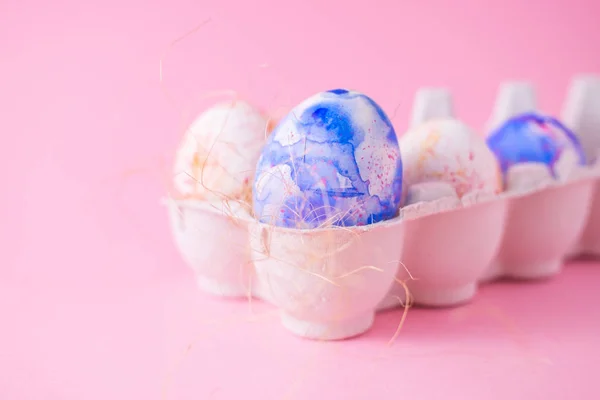Due uova di Pasqua decorate con classico acquerello blu, acquerello in cartone, stile minimalismo su fondo rosa chiaro. Decorazioni per le vacanze di Pasqua con spazio copia — Foto Stock
