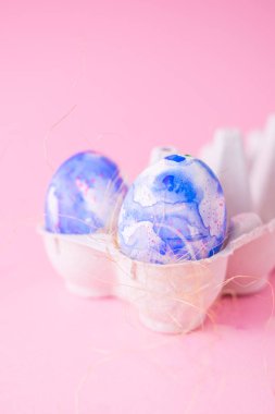 Klasik mavi suluboya akvaryumla süslenmiş iki paskalya yumurtası, sade pembe arka planda minimalizm tarzında. Fotokopi alanı olan Paskalya tatili dekorasyonları