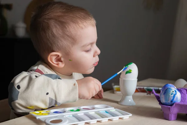 Toddler boy painting easter eggs preparing for holidays. Easter tradition