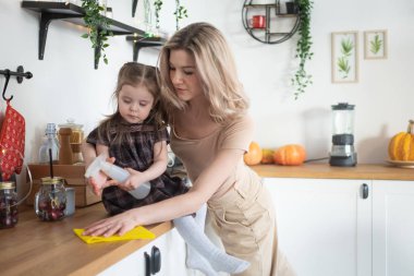 Young mother making domestic work at kitchen with her toddler daughter. Domestic life clipart
