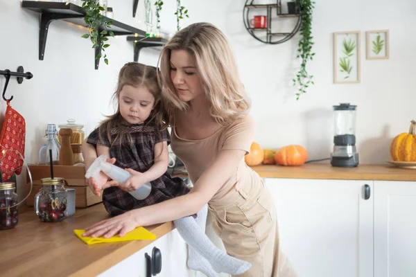 Young mother making domestic work at kitchen with her toddler daughter. Domestic life