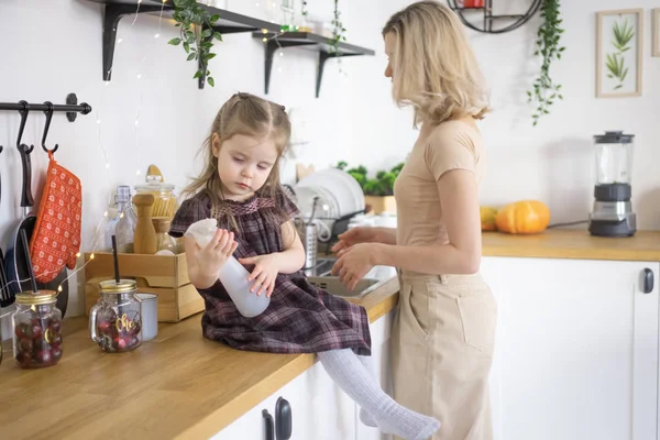 Jeune mère faisant des travaux ménagers à la cuisine avec sa fille tout-petit. Vie domestique — Photo