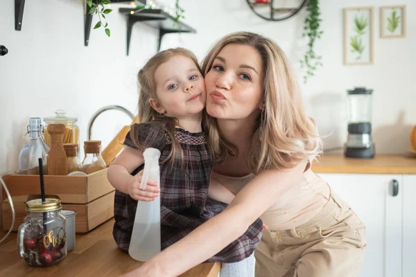 Young mother making domestic work at kitchen with her toddler daughter. Domestic life