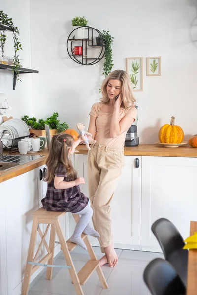 Jonge moeder werken vanuit huis per telefoon en laptop met haar peuter dochter — Stockfoto